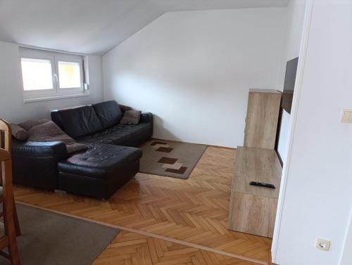 un soggiorno con divano nero e pavimento in legno di Stan na dan Brčko a Brčko