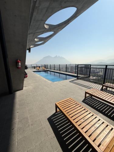 a patio with two benches and a swimming pool at Departamento Centro de Monterrey junto Paseo Santa Lucia y Macroplaza in Monterrey