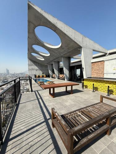 Una terraza en la azotea con bancos y una mesa en un edificio. en BARRIO W -The best place to rest in downtown MTY, en Monterrey