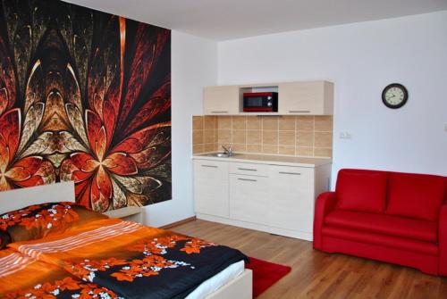 a bedroom with a bed and a red chair at Gyula Vár Prémium Apartman in Gyula