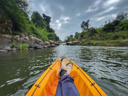 uma pessoa remando uma canoa amarela rio abaixo em Rafters Retreat Coorg - The Riverside Homestay em Srimangala