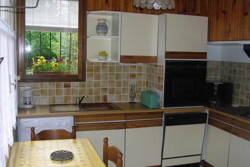 a kitchen with white cabinets and a table and a sink at Le Jardin in Gréoux-les-Bains
