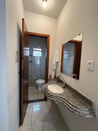 une salle de bain avec un lavabo, des toilettes et un miroir dans l'établissement Recanto Canuto, à Diamantina