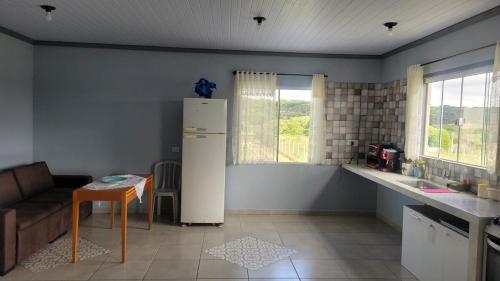eine Küche mit einem Kühlschrank, einem Tisch und einem Sofa in der Unterkunft Yad elohai pousada israelense in Campo Alegre