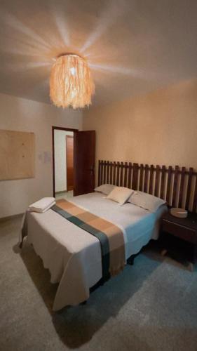 a bedroom with a large bed with a chandelier at Casa do Kite in Cumbuco