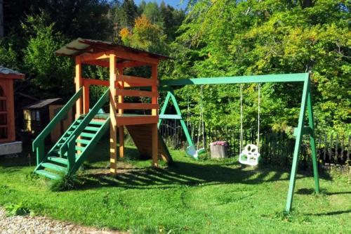 a playground with a slide and swings in the grass at Three Chalets Vrútky in Vrútky