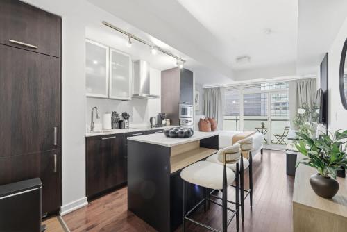 a kitchen with a counter and chairs in a room at Stylish Downtown Studio with CN Tower Views in Toronto