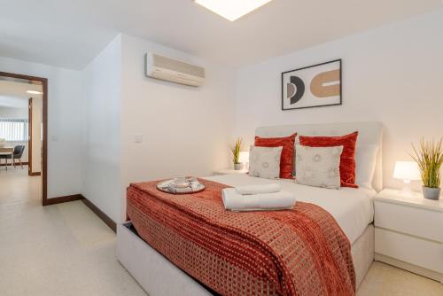 a white bedroom with a large bed with red pillows at Bom Sucesso Executive Suites by HostWise in Porto