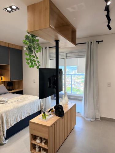 a bedroom with a bed and a tv on a table at Studio 107 Home Com Varanda, Ar-condicionado e Netflix in Mogi das Cruzes