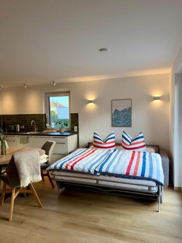 a bedroom with a bed with striped pillows and a kitchen at H24ZINGST - Das Ferienhaus in Zingst