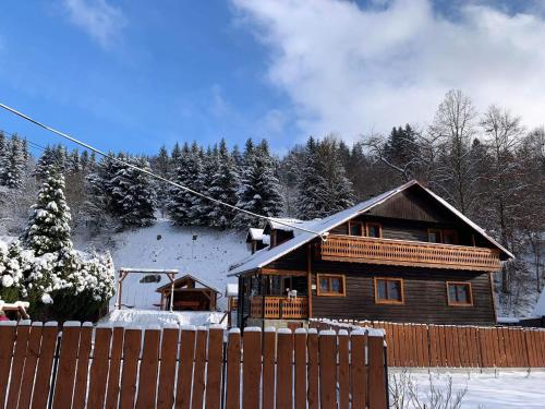 uma casa de madeira na neve com uma cerca em VILLA MARTINI em Lazy pod Makytou