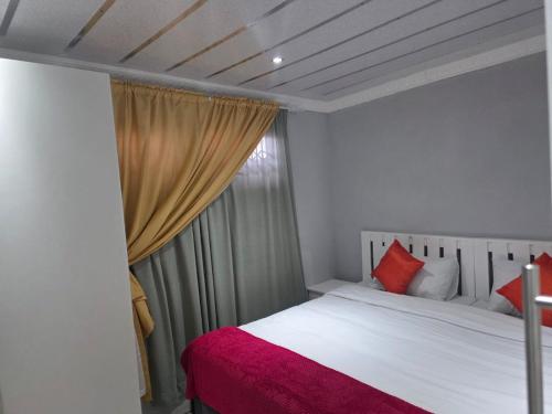 a bedroom with a bed with a red blanket and a window at Ngwanase Properties in Vosburg