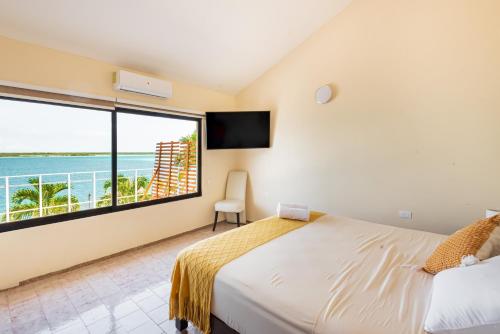 a bedroom with a bed and a large window at Casa Sirena - Habitaciones a orilla de la Laguna y Cenote Esmeralda in Bacalar