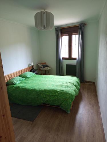 Un dormitorio con una cama verde y una ventana. en Apartamento Valdenieve, en Valdelinares