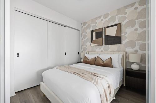 a bedroom with a white bed and a mirror at Modern West Getaway 2BR Condo with Free Parking in Toronto