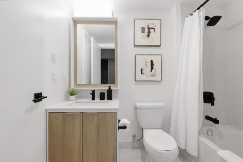 a bathroom with a toilet and a sink and a mirror at Modern West Getaway 2BR Condo with Free Parking in Toronto