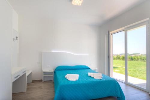 a white bedroom with a blue bed and a window at Conero Infinito in Numana
