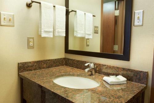 a bathroom with a sink and a mirror and towels at Heritage Inn & Suites San Antonio Airport, Trademark Wyndham in San Antonio