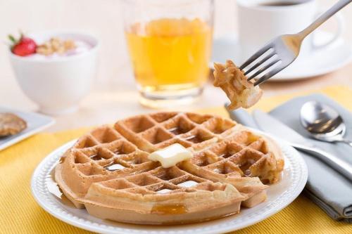 a plate of waffles with butter on a fork at Heritage Inn & Suites San Antonio Airport, Trademark Wyndham in San Antonio