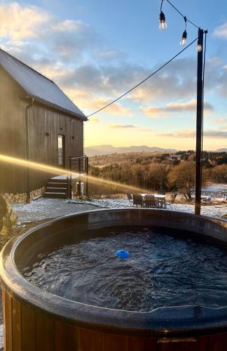 a hot tub in front of a building with the sunset at Vista - Domek Wakacyjny w Górach Sowich in Sierpnica