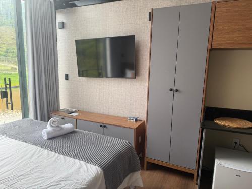 une chambre avec un lit et un bureau avec une télévision dans l'établissement Monakó Cabanas, à Bragança Paulista