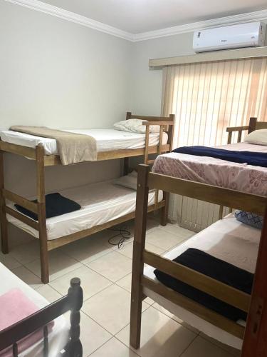 a room with three bunk beds and a window at Hospedagem Vermont in Maringá
