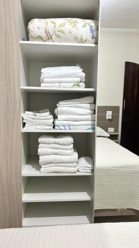 a closet filled with white towels and a bed at Casa em Santo André -SP in Santo André