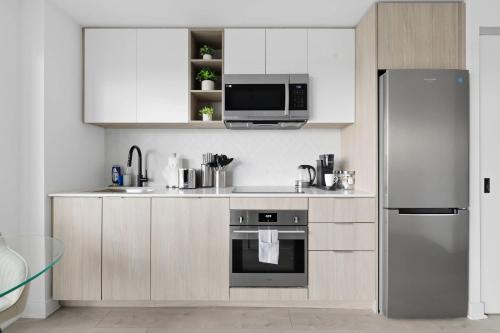 a kitchen with white cabinets and a stainless steel refrigerator at Skyline Studio with Stunning City Views & Parking in Toronto