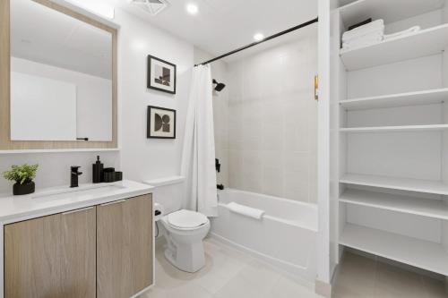 a bathroom with a toilet and a tub and a sink at Skyline Studio with Stunning City Views & Parking in Toronto