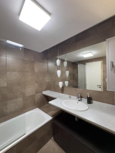 um banheiro com pia, banheira e espelho em Puerto Norte em Rosário