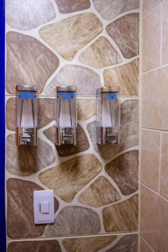 a bathroom with three glasses on a stone wall at S23 I City Lodge in Sabaneta
