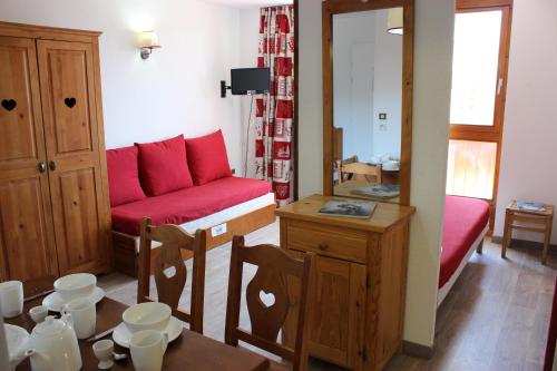 a living room with a red couch and a table at Altineige Appartements VTI in Val Thorens
