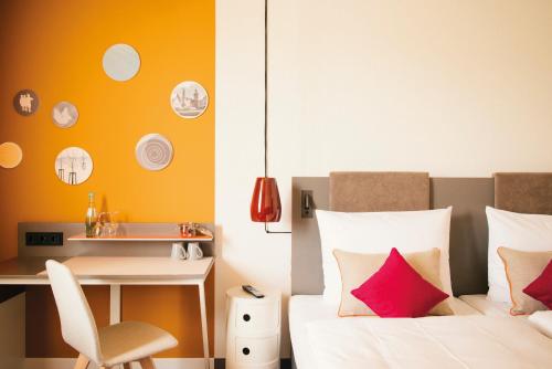 a bedroom with a bed and a desk and a chair at Vienna House Easy by Wyndham Limburg in Limburg an der Lahn