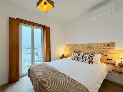 una camera da letto con un letto grande e una grande finestra di Mood Lodging Verso - Townhouse style home a Óbidos