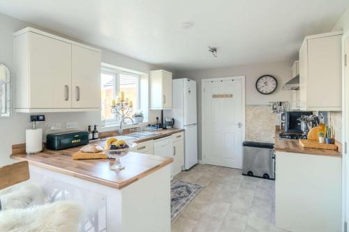 a kitchen with white cabinets and a counter top at Spacious Cotswolds Base, Private Garden & Parking in Evesham