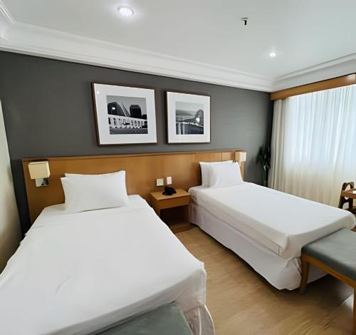 a hotel room with two beds and a window at Mediterrâneo Flat in Rio de Janeiro