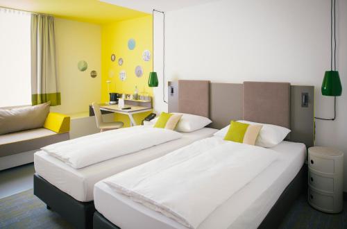 a hotel room with two beds and a couch at Vienna House Easy by Wyndham Limburg in Limburg an der Lahn