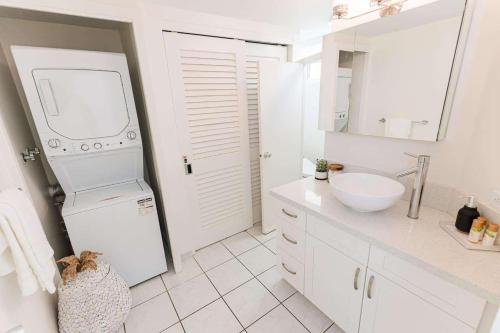 a white bathroom with a sink and a washing machine at Waikiki Shore 1014 in Honolulu