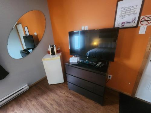 Cette chambre comprend une télévision et une commode avec un miroir. dans l'établissement Motel Le Victo, à Victoriaville