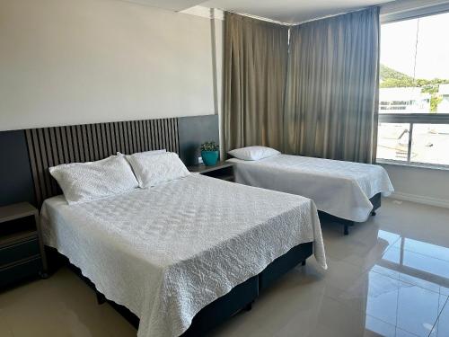 a hotel room with two beds and a window at Vieques in Bombinhas