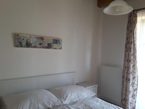 ein Schlafzimmer mit einem Bett und einem Bild an der Wand in der Unterkunft Malomkő Apartman in Zsira