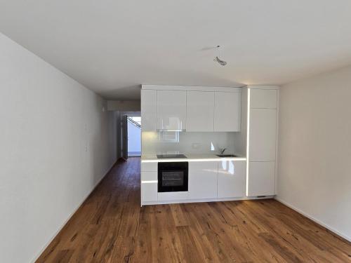 pusta kuchnia z białymi szafkami i drewnianą podłogą w obiekcie Urban Comfort, Zurich Airport - By River Glatt w mieście Opfikon