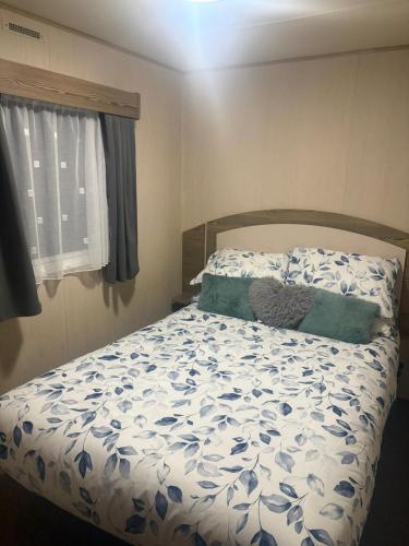 a bedroom with a bed with a blue and white comforter at Marton Mere 8 Berth Caravan in Blackpool
