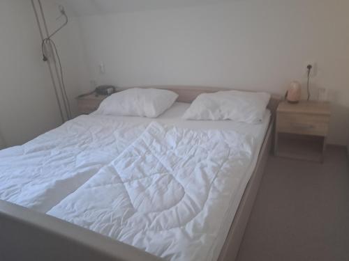 a white bed with white sheets and pillows at Gostišče Jelka, Hočko Pohorje in Pohorje