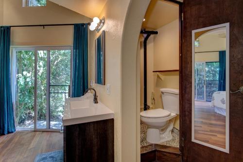 a bathroom with a toilet and a sink and a mirror at Balinese Beach House With Pool in Pahoa