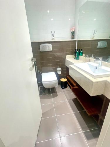 a bathroom with a sink and a toilet and a mirror at Marjan Island 1BR Beach Access & Cozy View - Private Exclusive in Ras al Khaimah