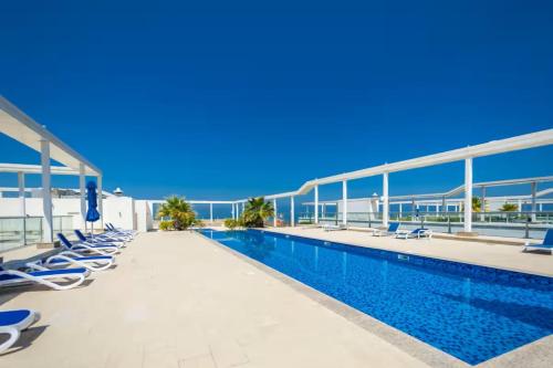 a swimming pool with chaise lounge chairs next to a building at Marjan Island 1BR Beach Access & Cozy View - Private Exclusive in Ras al Khaimah