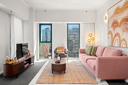 a living room with a pink couch and a tv at 17th on Flinders in Melbourne