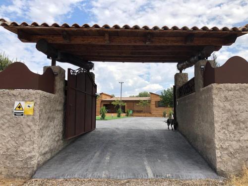 ein Tor zu einer Einfahrt, durch das ein Hund hindurchgeht in der Unterkunft Casa Rural Los Peralejos Piscina Privada en Cazorla in Cazorla
