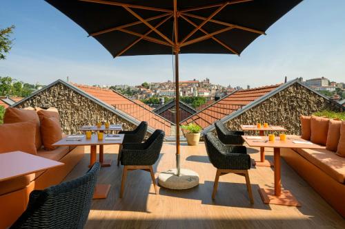 Un patio con mesas y sillas y una sombrilla. en Forte de Gaia, Autograph Collection, en Vila Nova de Gaia